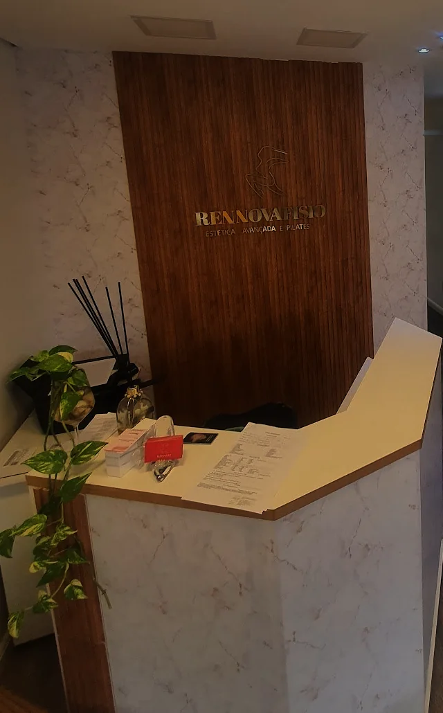 Balcão da recepção da Rennova, com painel de madeira ripada e o nome da clínica em letras douradas