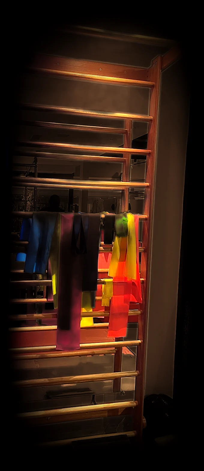 Espaldar: escada de madeira presa à parede, com faixas elásticas coloridas penduradas num dos degraus